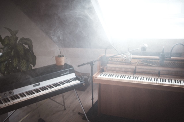 Fender Rhodes und Upright Piano im Gegenlicht des Dachfensters, Rauch im Raum.