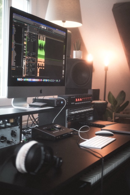 Schreibtisch mit iMac, Universal-Audio-Interface, Kopfhörern und Outboard-Rack.